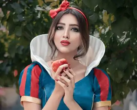 Mulher vestida de princesa segurando uma maçã nas vermelha