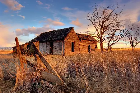 Pequena choupana no meio do campo, construída de madeira sob o céu de nuvens claras.